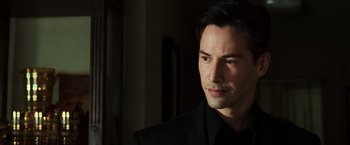 Movie still from “The Matrix” (1999), directed by Lana Wachowski – A person wearing a suit and tie; Close Up shot, Over the shoulder angle