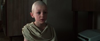 Movie still from “The Matrix” (1999), directed by Lana Wachowski – A young boy with a shaved head is looking at the camera; Close Up shot, High angle