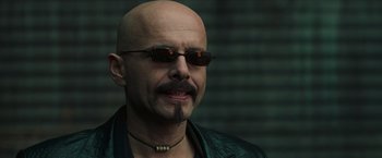 Movie still from “The Matrix” (1999), directed by Lana Wachowski – A bald man with a mustache wearing sunglasses; Close Up shot, Low angle