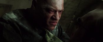 Movie still from “The Matrix” (1999), directed by Lana Wachowski – A bald man with a green neck tie; Close Up shot, Low angle
