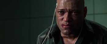 Movie still from “The Matrix” (1999), directed by Lana Wachowski – A bald man with headphones in his ears; Close Up shot, High angle