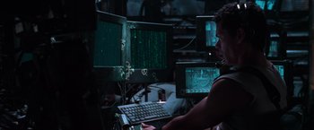 Movie still from “The Matrix” (1999), directed by Lana Wachowski – A man sitting in front of a computer monitor; Medium shot, Low angle
