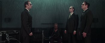 Movie still from “The Matrix” (1999), directed by Lana Wachowski – A group of men standing next to each other in the rain; Medium shot, Low angle