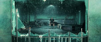 Movie still from “The Matrix” (1999), directed by Lana Wachowski – A man sitting on a chair in the middle of a room; Wide shot, High angle