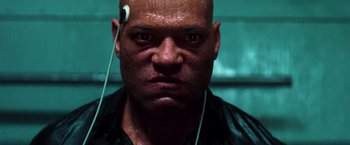 Movie still from “The Matrix” (1999), directed by Lana Wachowski – A bald man with headphones in his ears; Close Up shot, Low angle