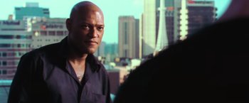 Movie still from “The Matrix” (1999), directed by Lana Wachowski – A man standing in front of a city skyline; Close Up shot, Over the shoulder angle