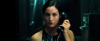 Movie still from “The Matrix” (1999), directed by Lana Wachowski – A beautiful woman holding a phone up to her ear; Close Up shot, Low angle