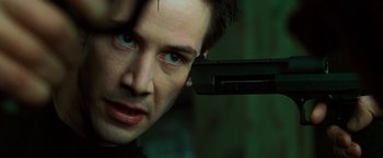 Movie still from “The Matrix” (1999), directed by Lana Wachowski – A person holding a gun; Close Up shot, Overhead angle