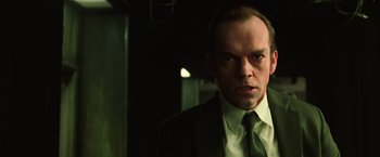 Movie still from “The Matrix” (1999), directed by Lana Wachowski – A person wearing a suit and tie; Close Up shot, Low angle