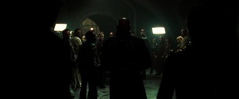 Movie still from “The Matrix Reloaded” (2003), directed by Lana Wachowski – A group of people standing in a dark room; Wide shot, Over the shoulder angle
