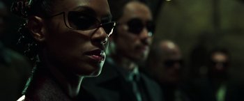Movie still from “The Matrix Reloaded” (2003), directed by Lana Wachowski – A man and a woman wearing sunglasses and a tie; Close Up shot, Low angle