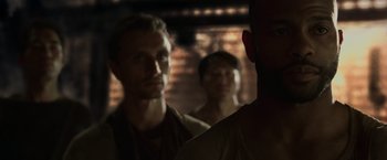 Movie still from “The Matrix Reloaded” (2003), directed by Lana Wachowski – A group of men standing next to each other in front of a brick wall; Close Up shot, Over the shoulder angle