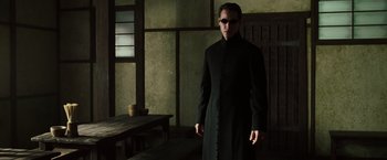 Movie still from “The Matrix Reloaded” (2003), directed by Lana Wachowski – A man in a black robe and sunglasses; Medium shot, Low angle