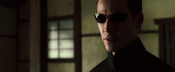 Movie still from “The Matrix Reloaded” (2003), directed by Lana Wachowski – A person wearing sunglasses; Close Up shot, Over the shoulder angle