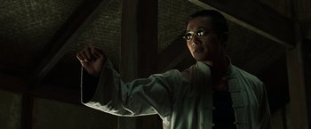 Movie still from “The Matrix Reloaded” (2003), directed by Lana Wachowski – A man wearing glasses is holding something in his hand; Close Up shot, Low angle