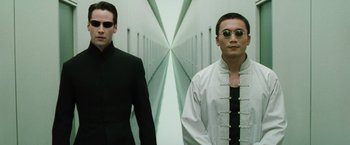 Movie still from “The Matrix Reloaded” (2003), directed by Lana Wachowski – A man and a woman standing next to each other in a hallway; Medium shot, Low angle