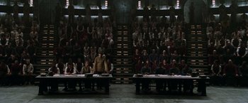 Movie still from “The Matrix Reloaded” (2003), directed by Lana Wachowski – A group of people sitting in front of a crowd; Extreme Wide shot, High angle