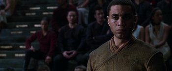 Movie still from “The Matrix Reloaded” (2003), directed by Lana Wachowski – A man standing in front of a group of people; Close Up shot, Over the shoulder angle