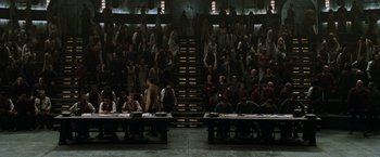 Movie still from “The Matrix Reloaded” (2003), directed by Lana Wachowski – A group of people sitting at tables in front of a crowd; Extreme Wide shot, High angle