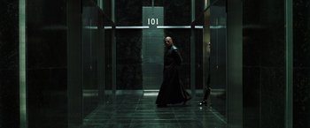 Movie still from “The Matrix Reloaded” (2003), directed by Lana Wachowski – A man in a long black coat walking in a building; Wide shot, High angle