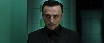 Movie still from “The Matrix Reloaded” (2003), directed by Lana Wachowski – A person wearing a suit and tie; Close Up shot, Low angle