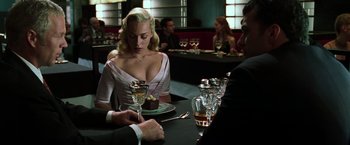 Movie still from “The Matrix Reloaded” (2003), directed by Lana Wachowski – A woman sitting at a table with a glass of wine; Medium shot, Over the shoulder angle
