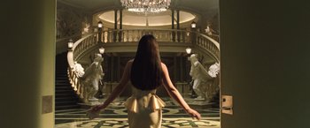 Movie still from “The Matrix Reloaded” (2003), directed by Lana Wachowski – A woman standing in front of a staircase in a room; Wide shot, Low angle