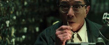 Movie still from “The Matrix Reloaded” (2003), directed by Lana Wachowski – An older man wearing glasses is holding a cigarette in his mouth; Close Up shot, Low angle