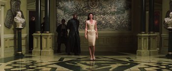 Movie still from “The Matrix Reloaded” (2003), directed by Lana Wachowski – A woman standing in front of a wall with a man standing in the background; Wide shot, Low angle