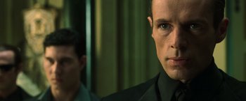 Movie still from “The Matrix Reloaded” (2003), directed by Lana Wachowski – A person wearing a suit and tie; Close Up shot, Over the shoulder angle