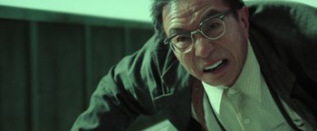 Movie still from “The Matrix Reloaded” (2003), directed by Lana Wachowski – An older man wearing glasses looking at the camera; Close Up shot, Low angle