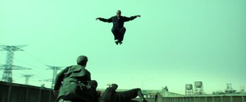 Movie still from “The Matrix Reloaded” (2003), directed by Lana Wachowski – A man flying through the air while holding his arms out; Wide shot, Low angle