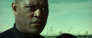 Movie still from “The Matrix Reloaded” (2003), directed by Lana Wachowski – A man's face in front of an oil field; Close Up shot, Low angle