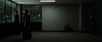 Movie still from “The Matrix Reloaded” (2003), directed by Lana Wachowski – A man sitting on the ground in a dark room; Wide shot, Over the shoulder angle
