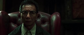 Movie still from “The Matrix Reloaded” (2003), directed by Lana Wachowski – An older man wearing a suit and glasses; Close Up shot, Low angle