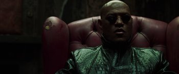 Movie still from “The Matrix Reloaded” (2003), directed by Lana Wachowski – A bald man wearing a leather jacket and sunglasses; Close Up shot, High angle