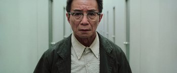 Movie still from “The Matrix Reloaded” (2003), directed by Lana Wachowski – An older man wearing glasses and a green jacket; Close Up shot, Low angle