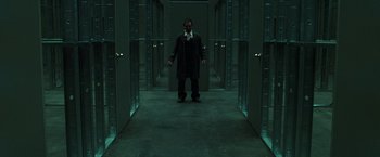 Movie still from “The Matrix Reloaded” (2003), directed by Lana Wachowski – A man standing in a dark hallway with many doors; Wide shot, Low angle