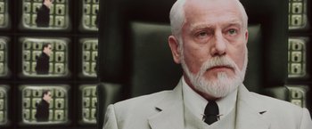 Movie still from “The Matrix Reloaded” (2003), directed by Lana Wachowski – An older man with a beard and a suit and tie; Close Up shot, Low angle