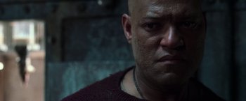 Movie still from “The Matrix Reloaded” (2003), directed by Lana Wachowski – A man with a bald head is looking at the camera; Close Up shot, Low angle