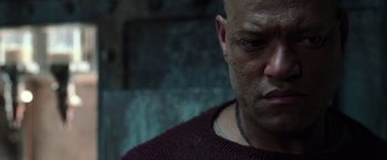 Movie still from “The Matrix Reloaded” (2003), directed by Lana Wachowski – A man with a shaved head is looking at the camera; Close Up shot, Low angle