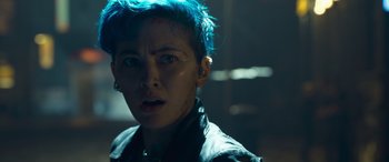 Movie still from “The Matrix Resurrections” (2021), directed by Lana Wachowski – A woman with blue hair looking at the camera; Close Up shot, Over the shoulder angle