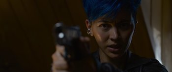 Movie still from “The Matrix Resurrections” (2021), directed by Lana Wachowski – A person with blue hair holding a gun; Close Up shot, Low angle