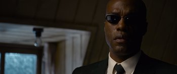 Movie still from “The Matrix Resurrections” (2021), directed by Lana Wachowski – A person wearing a suit and sunglasses; Close Up shot, Low angle
