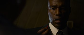 Movie still from “The Matrix Resurrections” (2021), directed by Lana Wachowski – A man in a suit and tie holding a red pencil; Close Up shot, Low angle