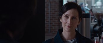 Movie still from “The Matrix Resurrections” (2021), directed by Lana Wachowski – A person wearing a jacket with a brick wall in the background; Close Up shot, Over the shoulder angle