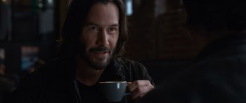 Movie still from “The Matrix Resurrections” (2021), directed by Lana Wachowski – A person holding a cup of coffee; Close Up shot, Over the shoulder angle