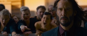 Movie still from “The Matrix Resurrections” (2021), directed by Lana Wachowski – A group of people in a room with a man in a suit; Close Up shot, Over the shoulder angle