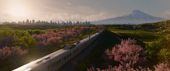 Movie still from “The Matrix Resurrections” (2021), directed by Lana Wachowski – A train traveling on a track near a lush green field; Extreme Wide shot, Low angle