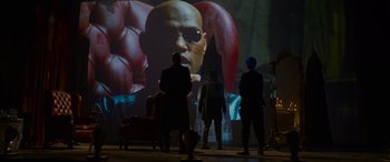 Movie still from “The Matrix Resurrections” (2021), directed by Lana Wachowski – A group of people standing in front of a projection screen; Wide shot, Low angle